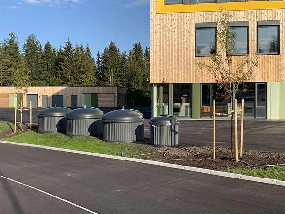 SemiQ delvis nedgravde beholdere ved skolebygg, integrert i moderne landskap med asfalt og grønne områder.