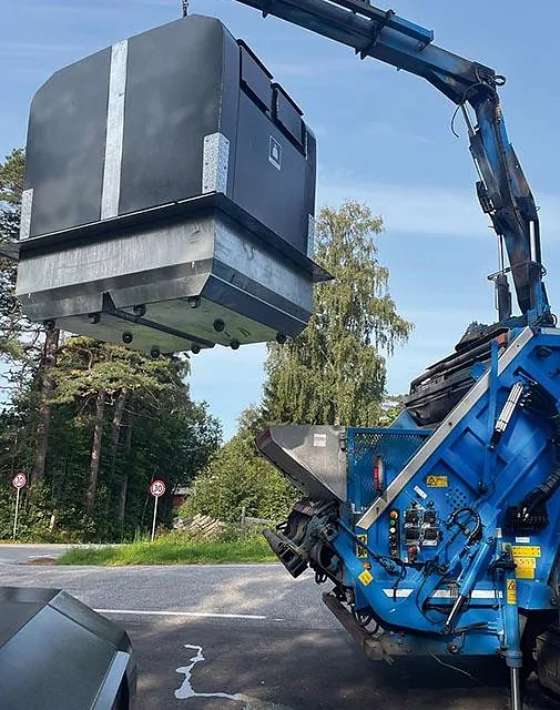 Semi-underjordisk container løftes med kran under tømming